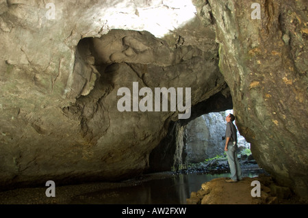 Homme debout dans la grotte sous l'zelske jama mali plus naravni (le petit pont naturel) dans la région de Rakov Skocjan, Slovénie Banque D'Images