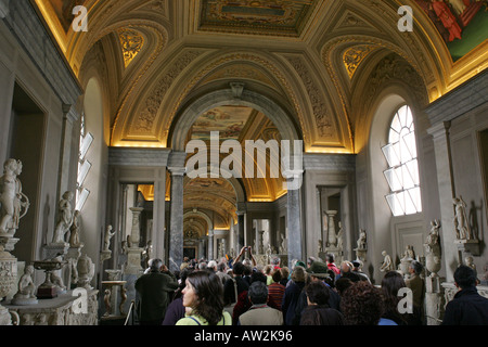 Les touristes d'admirer les statues et sculptures dans un couloir lumineux avec plafond peint du musée du Vatican, Rome Italie Europe Banque D'Images