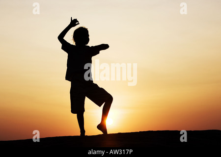 Indian girl dancing silhouette sur un rocher au coucher du soleil. L'Inde Banque D'Images