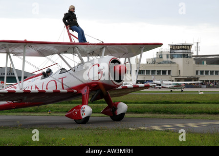 Un guinot wingwalker debout sur un avion en attente de rendez-vous sur la piste. Banque D'Images