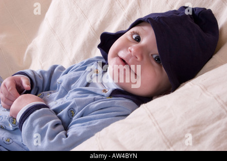 Portrait cute baby boy in hooded babygro smiling Banque D'Images