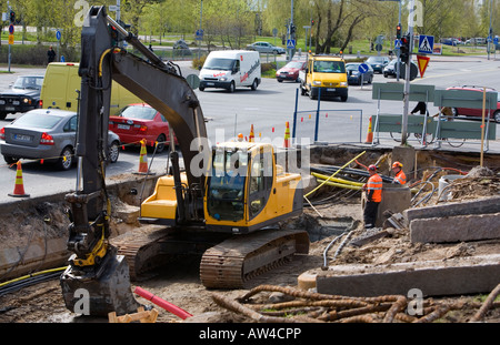 Deux travailleurs de l'installation de nouveaux tuyaux de système de drainage assistée par un digger , Finlande Banque D'Images