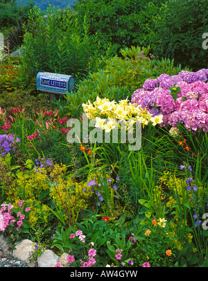 Boîte aux lettres de mosaïques par artiste Elaine Summers promettant des lettres d'amour dans un lit de jardin de vivaces d'été dans un chalet jardin Banque D'Images