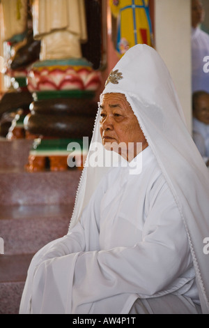 Une vieille femme prêtre CAO DAI attend une cérémonie de prière au Grand Temple de CAO DAI VILLAGE TAY NINH VIETNAM Banque D'Images