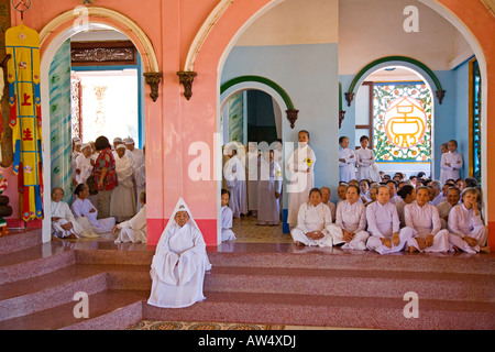 Une femme PRÊTRE CAO DAI est assis devant ses partisans à l'intérieur du grand temple de CAO DAI VILLAGE TAY NINH VIETNAM Banque D'Images