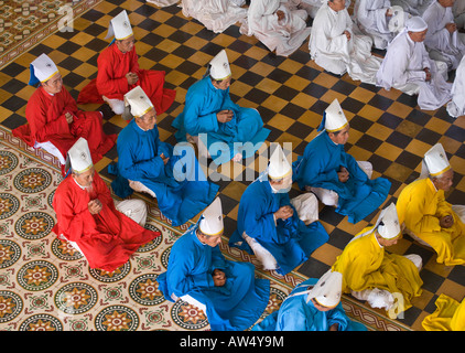 Taoïste et Bouddhiste, les membres du clergé chrétien prier lors d'une cérémonie à l'intérieur du grand temple de CAO DAI VILLAGE TAY NINH VIETNAM Banque D'Images