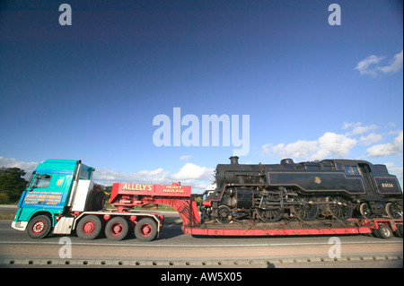 Train locomotive à vapeur d'être transportés par la route sur une remorque surbaissée, Leicestershire, UK Banque D'Images