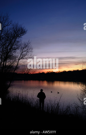 La silhouette de la figure d'un homme à temps le soir à Tittisworth,au réservoir dans le Staffordshire en Angleterre. Banque D'Images