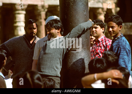 Inde Delhi Qutb Minar Hommes essayant de mettre leurs bras autour du pilier de fer Banque D'Images