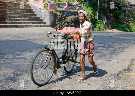 Man pushing bicycle, bouteille de gaz et la pente, Meenkunnam, Kerala, Inde Banque D'Images