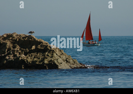 Bateau à voile avec red sails en passant devant un rocher dans la mer très bleue Dorset UK Banque D'Images