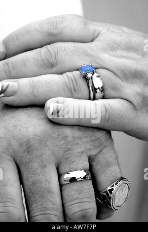 Close up de mains d'un couple de jeunes mariés montrant outre de leur mariage en mono mais avec le saphir bleu toujours en couleur Banque D'Images