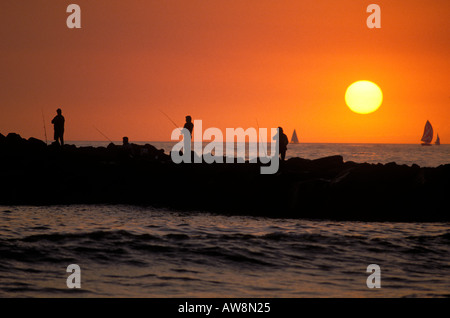 Silhouette de personnes sur la pêche jetée avec coucher de soleil orange et voiliers en arrière-plan Ventura en Californie Banque D'Images