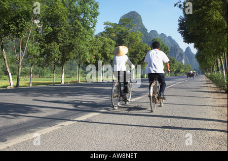 Couple Riding Bicycles le long de la route à travers les rizières, Yangshuo Banque D'Images