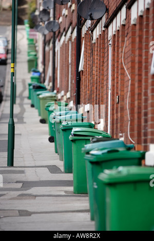 Une rangée de poubelles vertes en attente d'être recueillies sur un trottoir à Nottingham, Royaume-Uni Banque D'Images