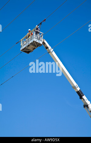 Les travailleurs de service de maintenance travaillant sur la ligne d'alimentation électrique hydro à partir d'une grue Banque D'Images