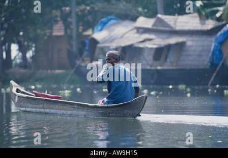 Voile l'homme dans une pirogue sur l'eau dormante Keralan, dans le sud de l'Inde Banque D'Images