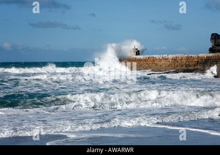 L'état de la mer et une vague s'écraser contre Portreath pier. Banque D'Images