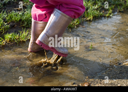 Image d'un enfant en rose bottes de s'éclabousser dans les flaques Banque D'Images