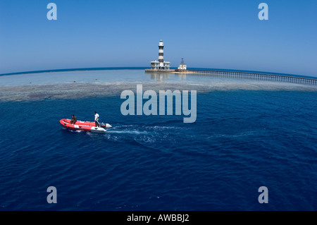 Bateau pneumatique bateau de plongée en face de Daedalus Reef isolé avec phare britannique du 19e siècle construit dans la Mer Rouge Banque D'Images