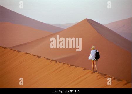 Fille qui marche seul sur la Dune 45 au lever du soleil en Namibie, Afrique du Sud Banque D'Images