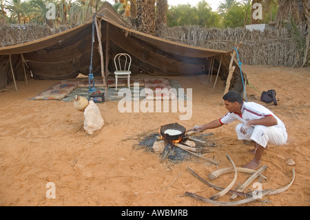 La cuisine d'un homme en face d'une tente à l'oasis de Ksar Ghilane, dans le désert du Sahara au sud de la Tunisie. Banque D'Images