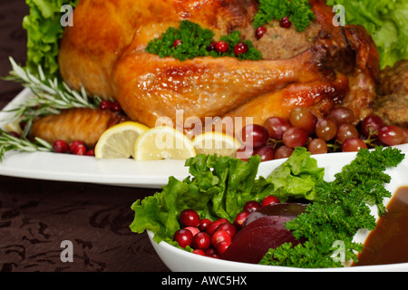 La dinde rôtie farcie entière avec sauce sur une assiette blanche avec un dîner de Noël végétarien sur la table, vente en tête sur Alamy, horizontal aux États-Unis US haute résolution Banque D'Images