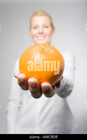 Blond woman holding orange en riant Banque D'Images