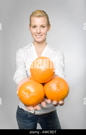 Blond woman holding orange en riant Banque D'Images