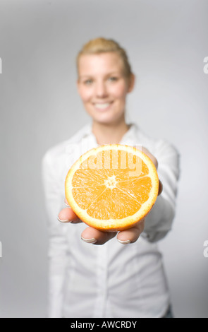 Blond woman holding orange en tranches Banque D'Images