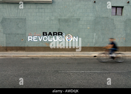 Man on bicycle sifflant passé la propagande politique peint sur un mur à Cienfuegos, Cuba, Caraïbes, Amériques Banque D'Images