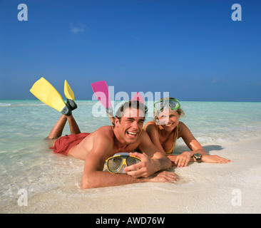 Jeune couple avec matériel de plongée en eaux peu profondes, sur la plage, Maldives, océan Indien Banque D'Images