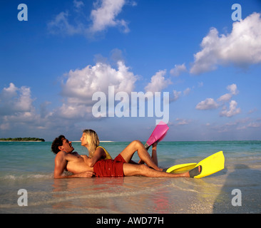 Jeune couple avec matériel de plongée en eaux peu profondes, sur la plage, Maldives, océan Indien Banque D'Images