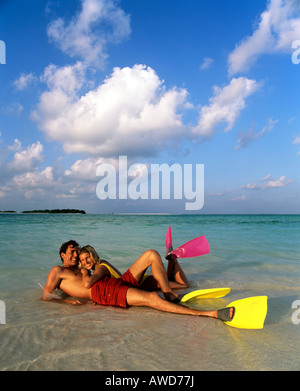 Jeune couple avec matériel de plongée en eaux peu profondes, sur la plage, Maldives, océan Indien Banque D'Images