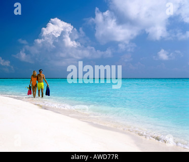 Jeune couple avec matériel de plongée autour de l'eau peu profonde, de sable, Maldives, océan Indien Banque D'Images