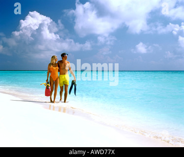 Jeune couple avec matériel de plongée autour de l'eau peu profonde, de sable, Maldives, océan Indien Banque D'Images