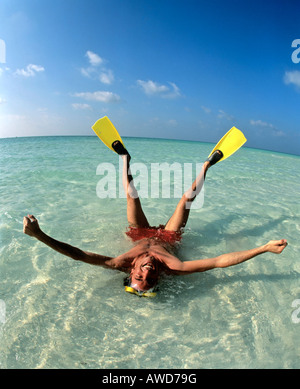 Jeune homme portant des palmes portant en eau peu profonde, locations, Maldives, océan Indien Banque D'Images