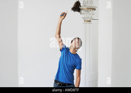 Man dusting lustre de cristal dans la maison Banque D'Images