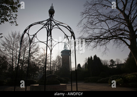 Une pergola en fer forgé couvre une statue avec le Carillon de clocher dans silohuetted l'arrière-plan. Loughborough, Angleterre. Banque D'Images