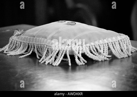 Deux anneaux de mariage posé sur un coussin de velours sur un bureau en bois noir blanc Banque D'Images