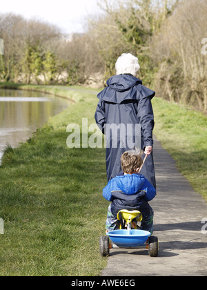 En tirant le long de petit-fils de mamie sur tricycle, Canal de Bude, Cornwall, UK Banque D'Images