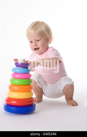 Petite fille jouant sur le plancher avec anneaux de couleurs Banque D'Images