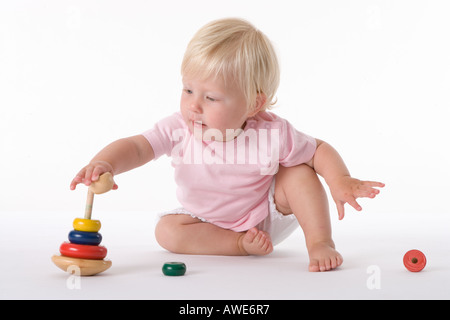 Petite fille assise sur le sol avec un jouet Banque D'Images