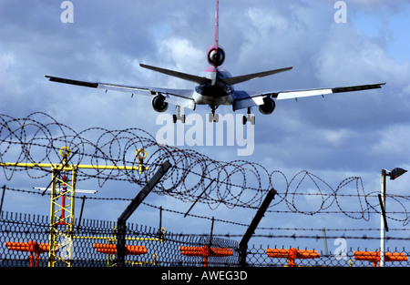 Un Nord West jet décolle de l'aéroport de Londres Gatwick sur le fil barbelé clôture de sécurité Banque D'Images