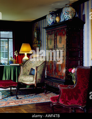 Lampe allumée sur la table à côté d'un fauteuil dans le salon traditionnel avec de grands vases chinois sur un grand placard chinois Banque D'Images