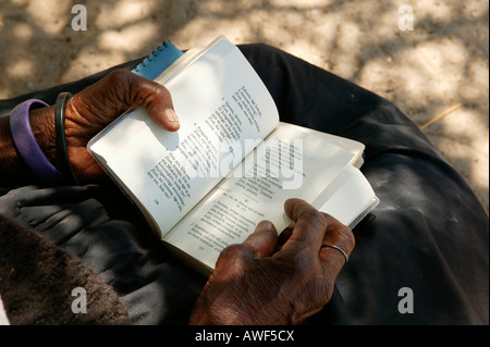 Femme âgée de tourner les pages d'un livre de cantiques, Sehitwa, Botswana, Africa Banque D'Images