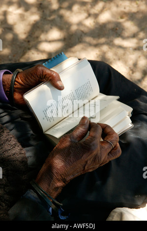 Femme âgée de tourner les pages d'un livre de cantiques, Sehitwa, Botswana, Africa Banque D'Images