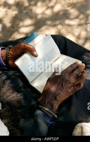 Femme âgée de tourner les pages d'un livre de cantiques, Sehitwa, Botswana, Africa Banque D'Images