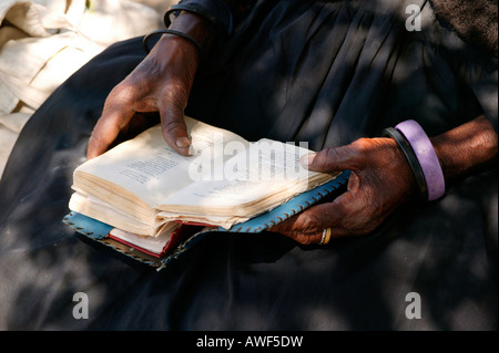 Femme âgée de tourner les pages d'un livre de cantiques, Sehitwa, Botswana, Africa Banque D'Images