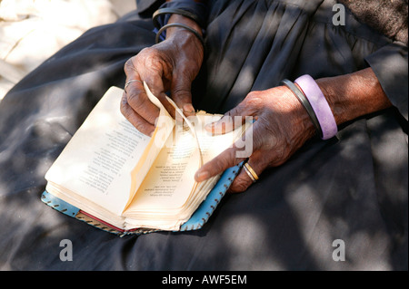 Femme âgée de tourner les pages d'un livre de cantiques, Sehitwa, Botswana, Africa Banque D'Images